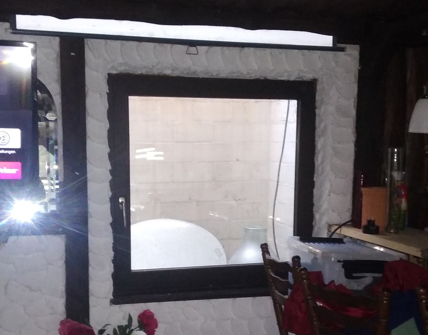 Window in dark stone wall, interior with light furnishings and furniture