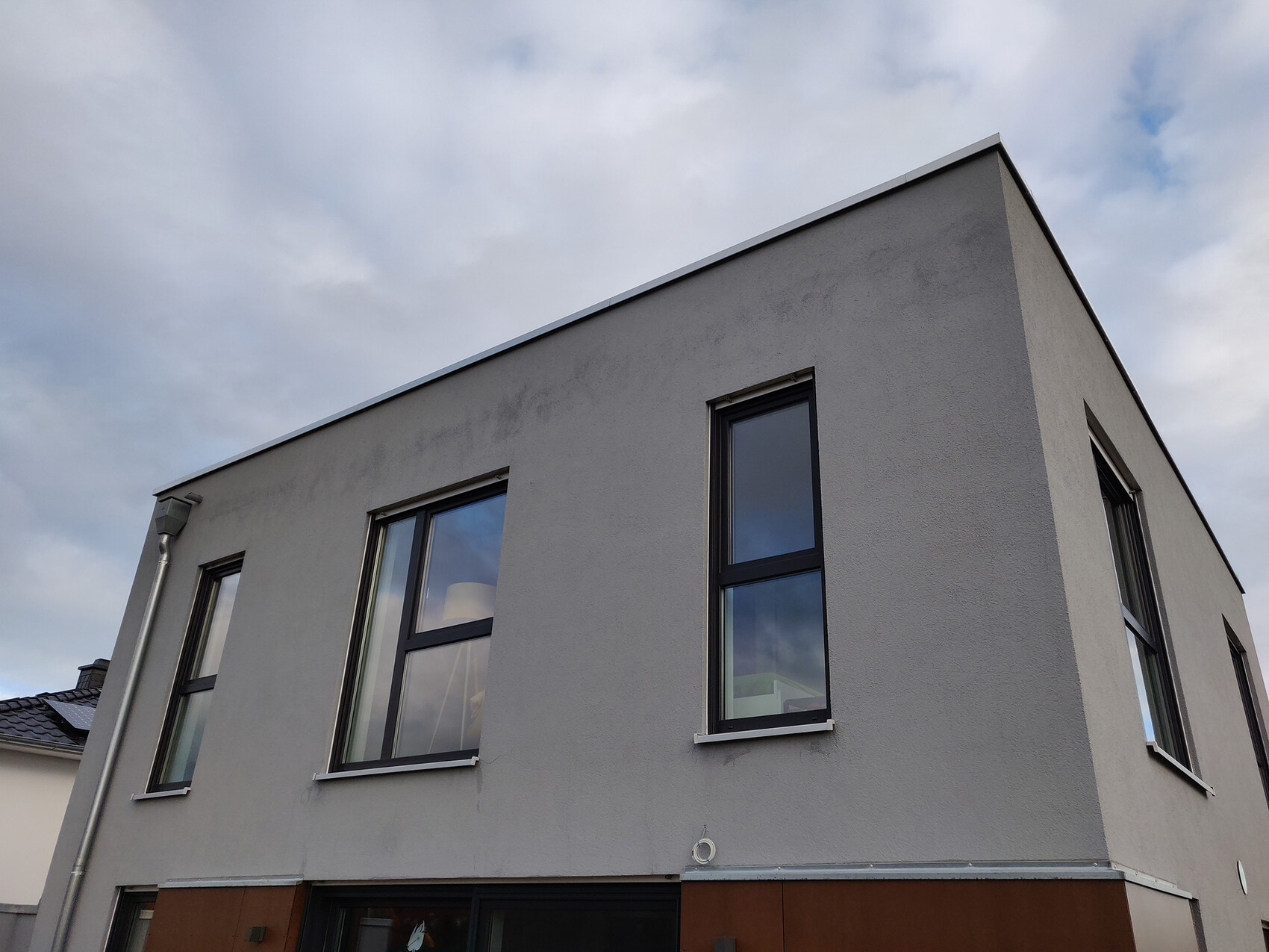 Modern grey house facade with large rectangular windows on a corner