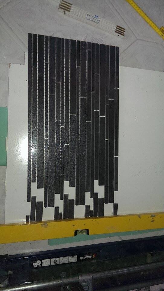 Black, narrow mosaic tiles arranged vertically on a bathroom wall.