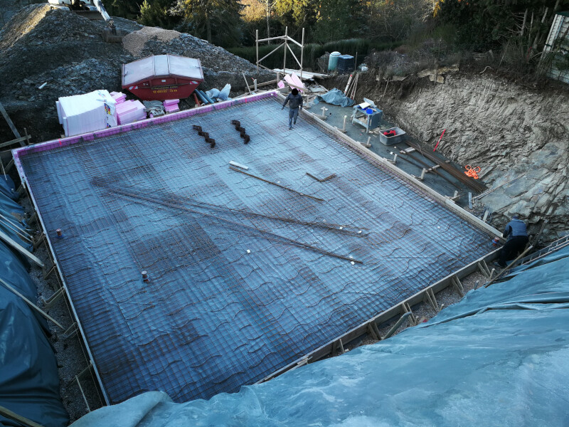 Construction pit with steel reinforcement (reinforcement mesh) on building footprint, workers at work.