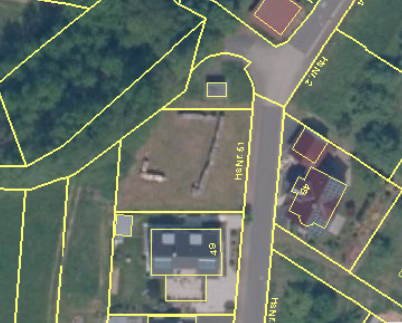 Aerial view of a building plot with yellow marked plot boundaries and buildings