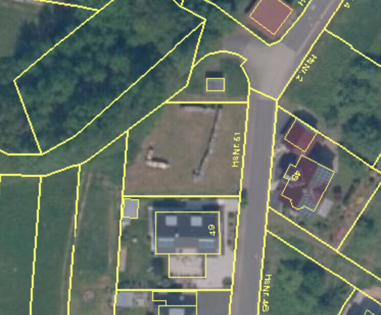 Aerial view of a residential area with yellow plot lines, streets, and buildings.