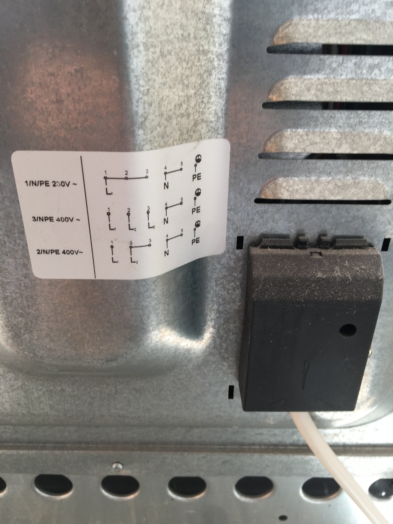 Close-up of a metal housing with wiring diagram sticker and black connection module