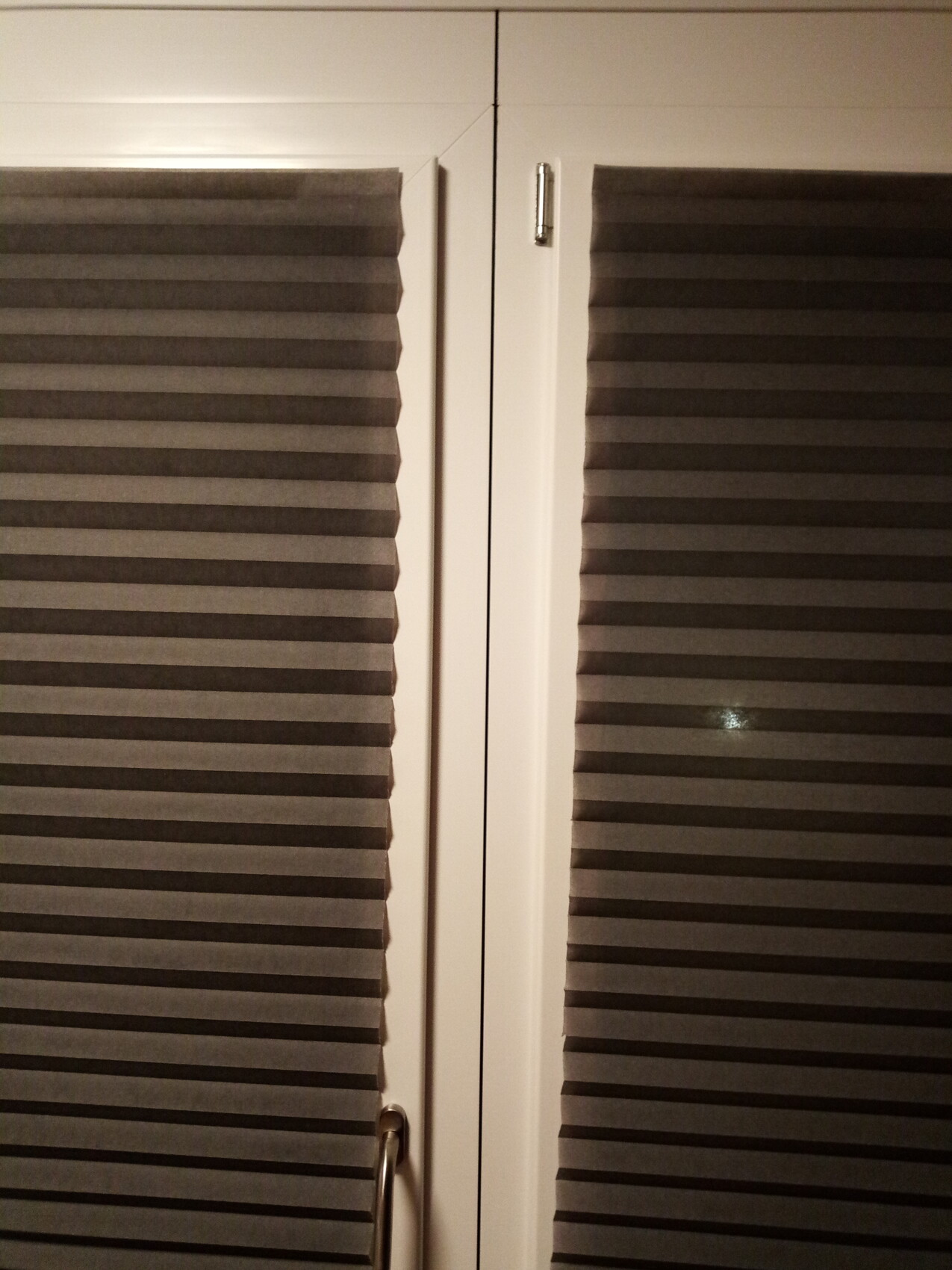 White double doors with horizontal slats, central dividing strip, handle at bottom left.