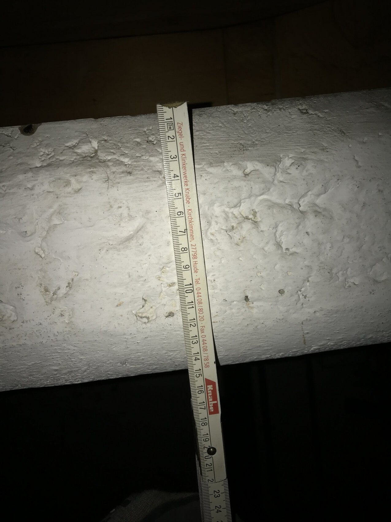 Measuring tape over raw concrete beam at construction site in shell stage.