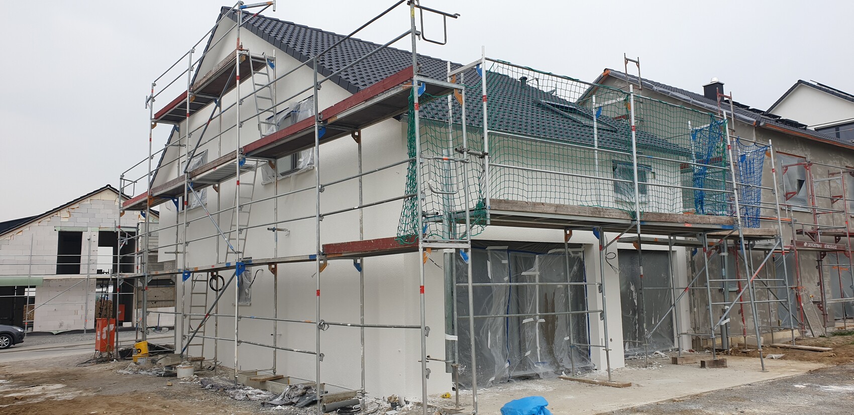 Baugerüst vor einem Wohnhaus, Bauarbeiten, Netze und abgedeckte Fenster.