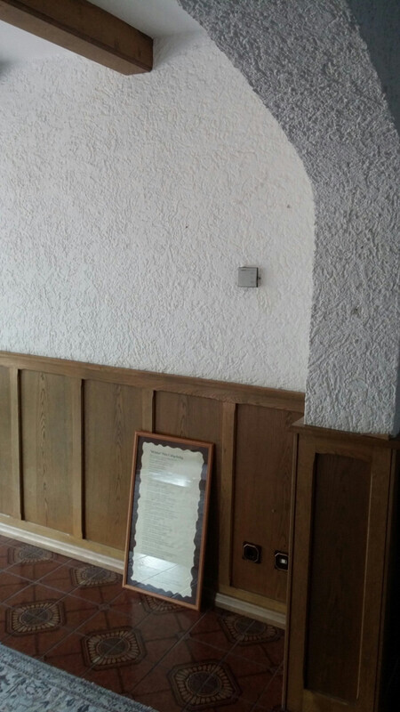 White textured interior wall with wood cladding, arch design, and tiled floor