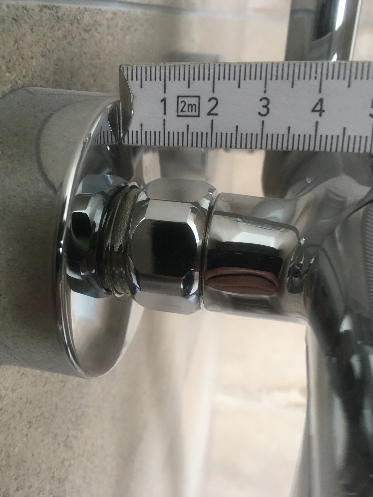 Chromium bathroom fitting with measuring tape, close-up of the connection
