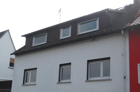 Exterior view of a white house with a dark roof and dormers