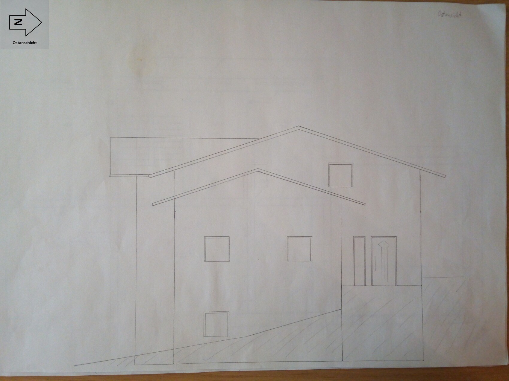 Architectural drawing of a house front with gable roof, windows, and entrance