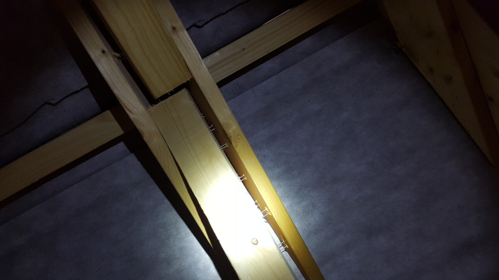 Timber frame construction in the attic with nails and insulation
