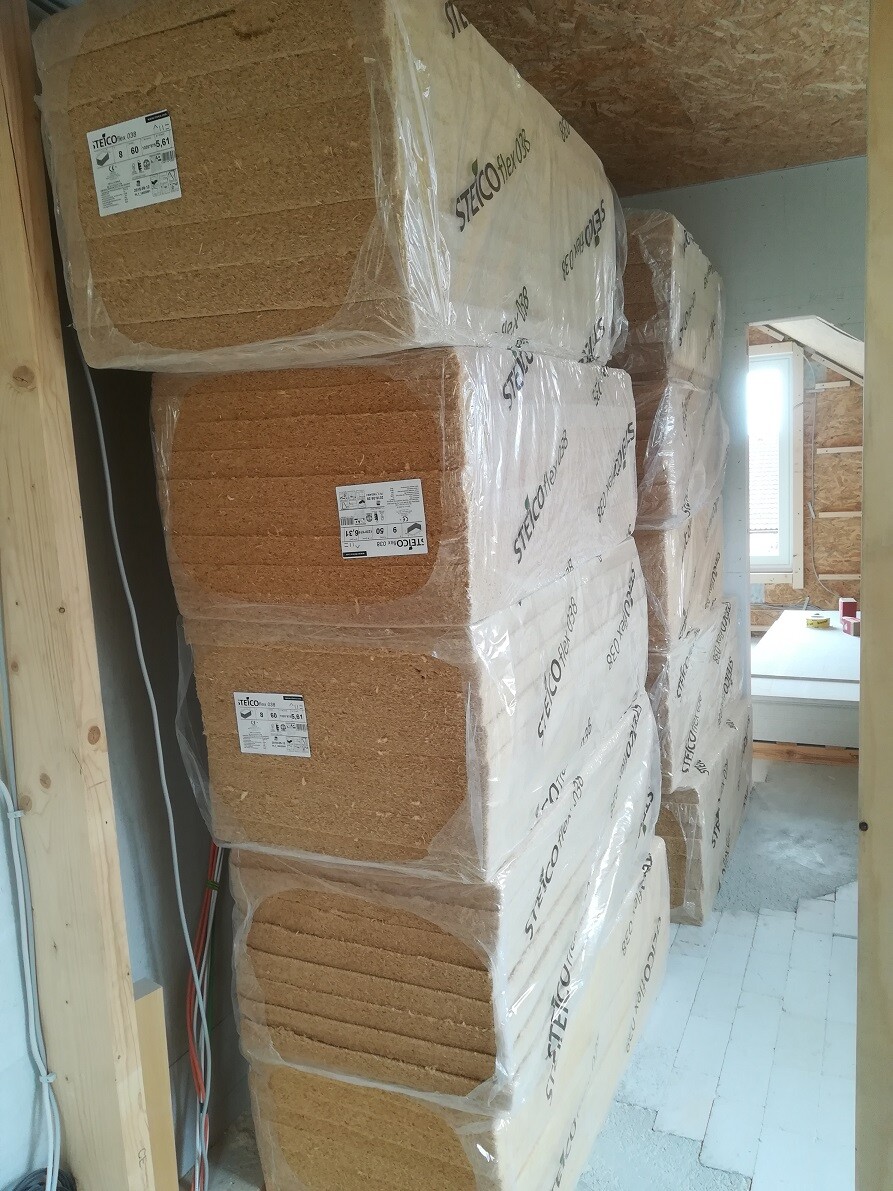 Several wood fiber insulation boards (Steico) wrapped in plastic, stacked in the construction area.