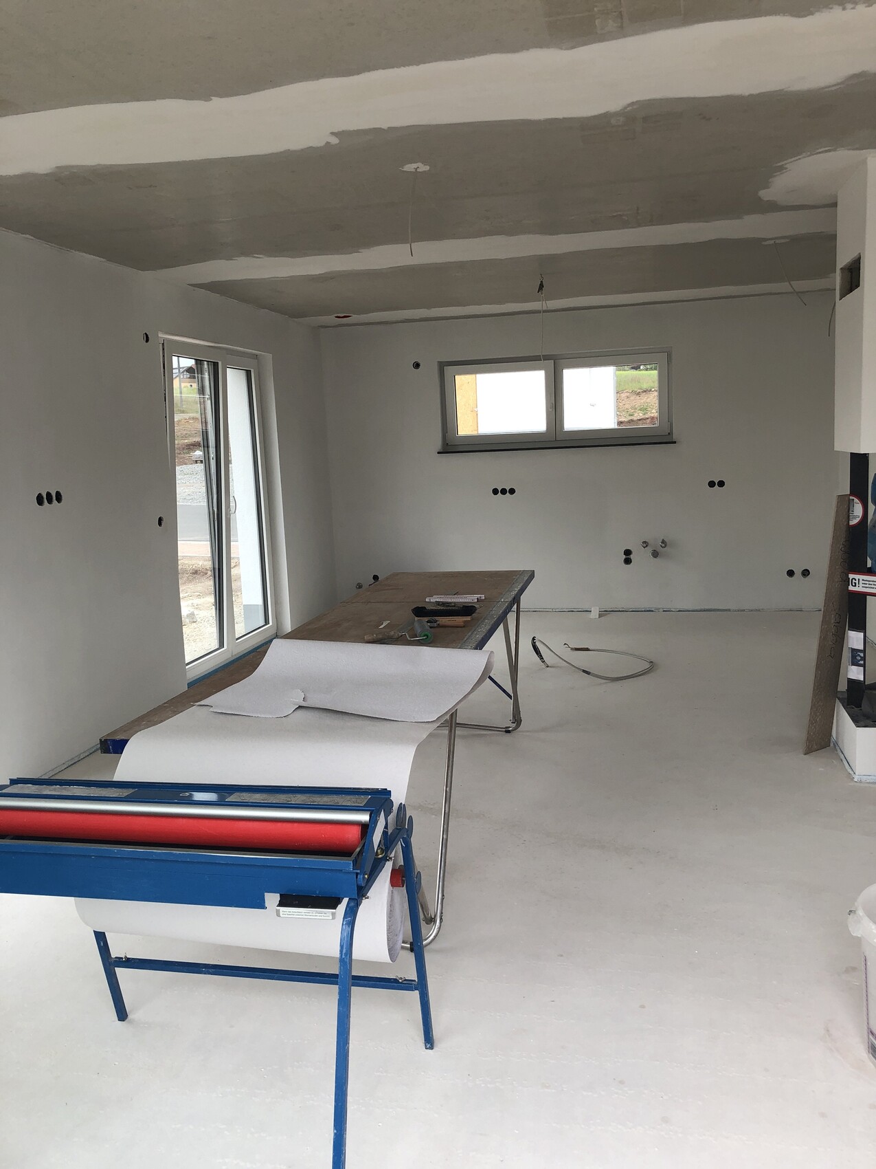 Unfinished interior with workbench, roll of paper, tools and windows.