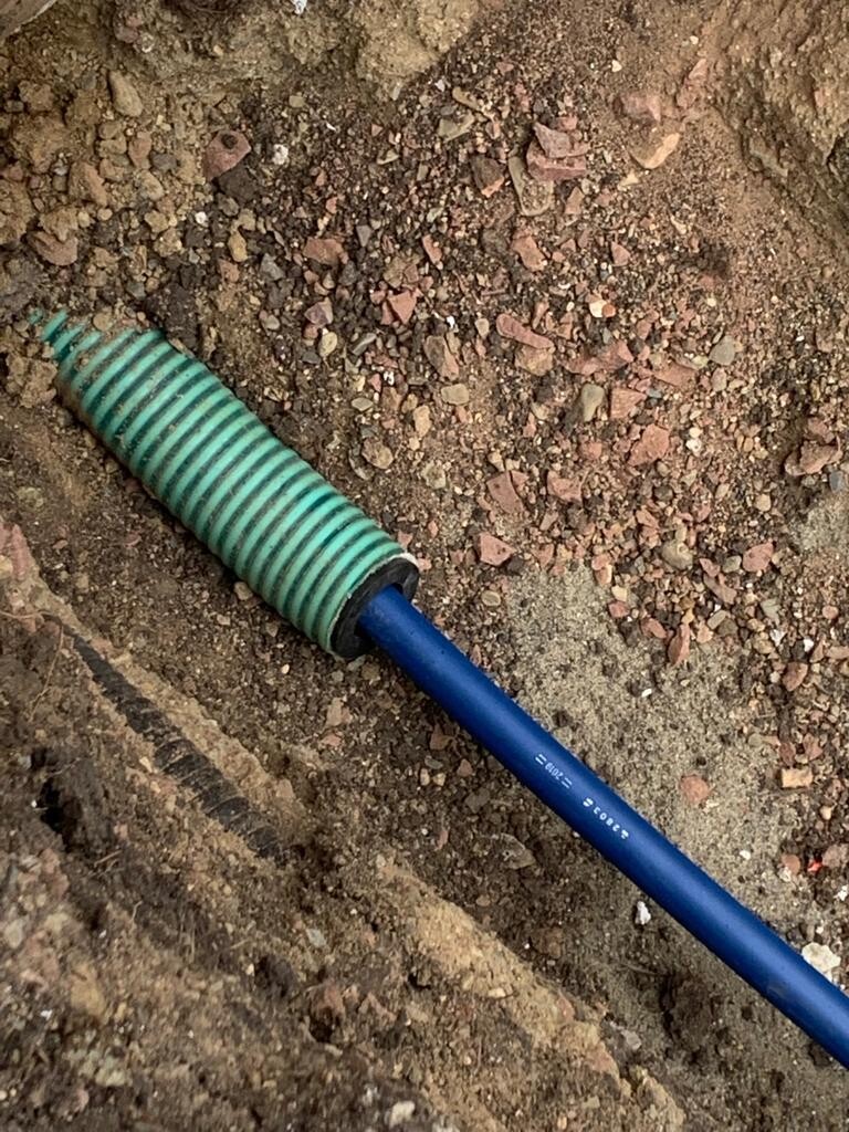 Blue cable line with green spiral protective hose in the soil