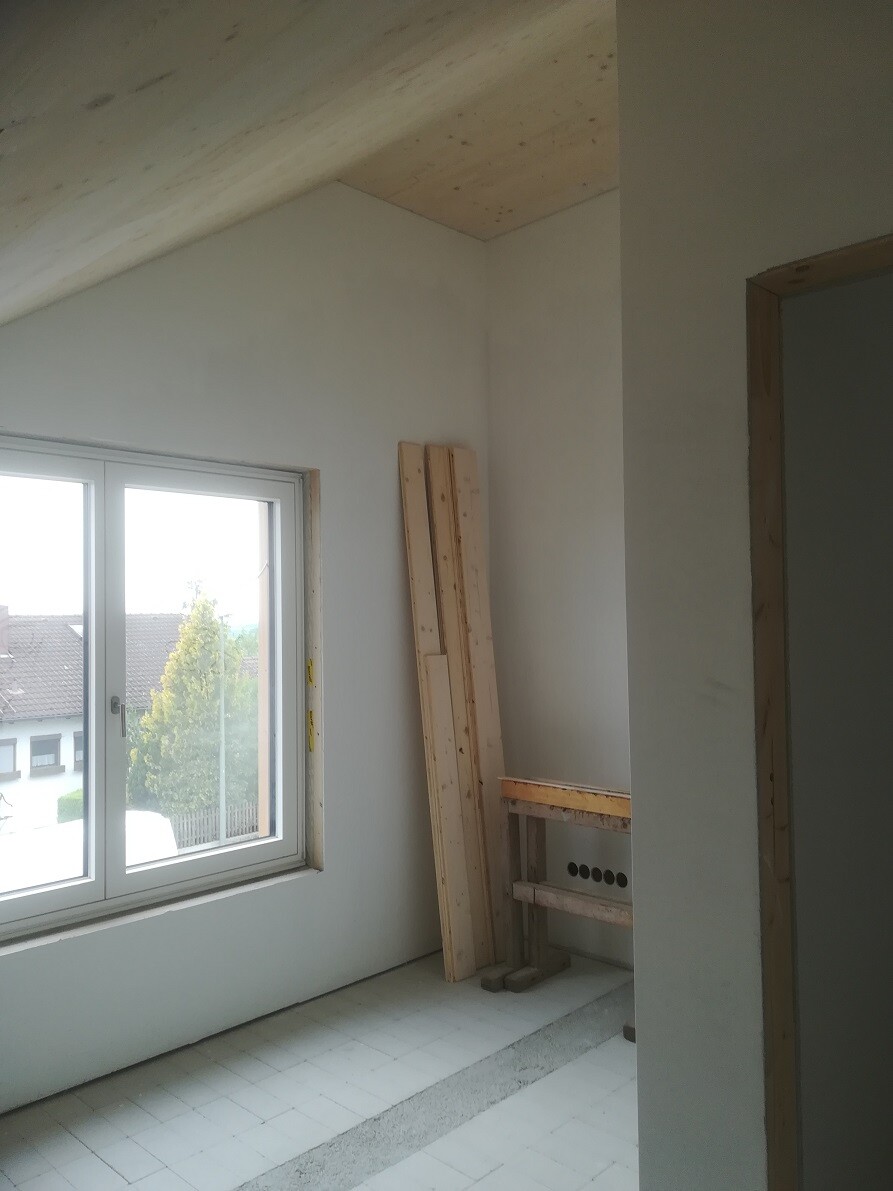 Unfinished room with window, wooden battens, workbench and construction work.