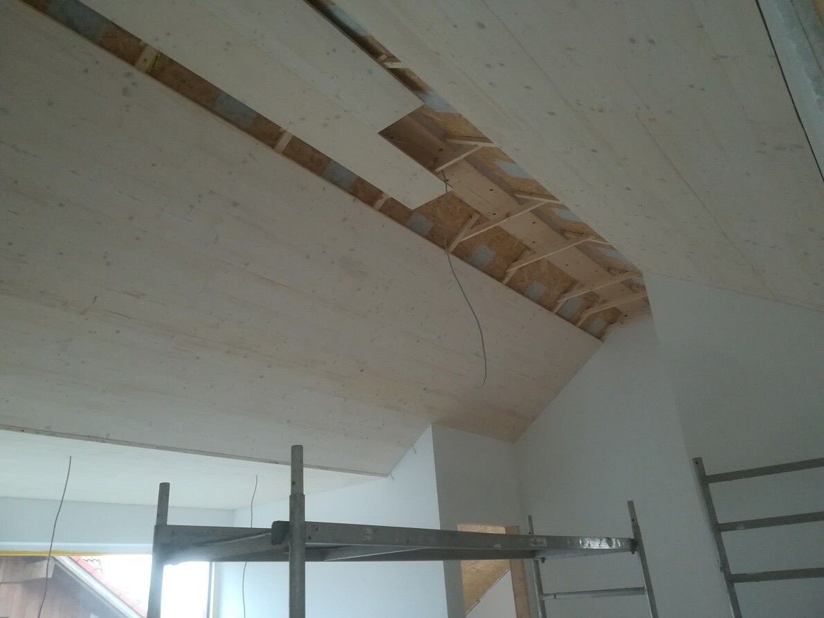 View of unfinished ceiling structure: wooden panels, OSB, cables and scaffolding.