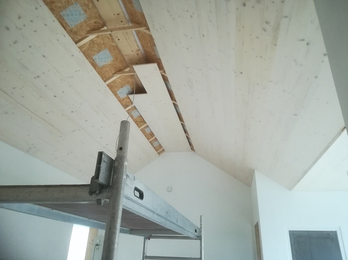 Unfinished interior with OSB ceiling, construction scaffolding and white walls.