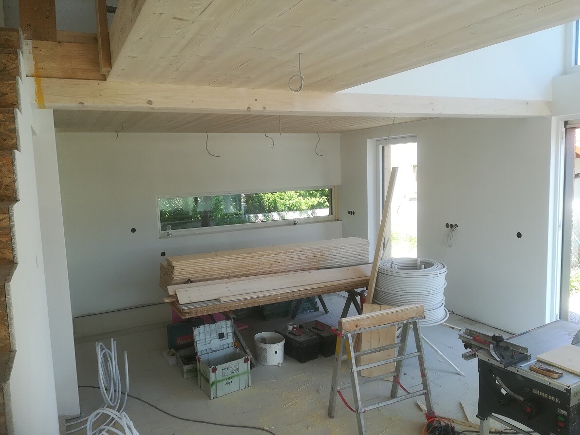 Interior of a shell construction: wooden ceiling, stacked boards, cable drums, construction tools.