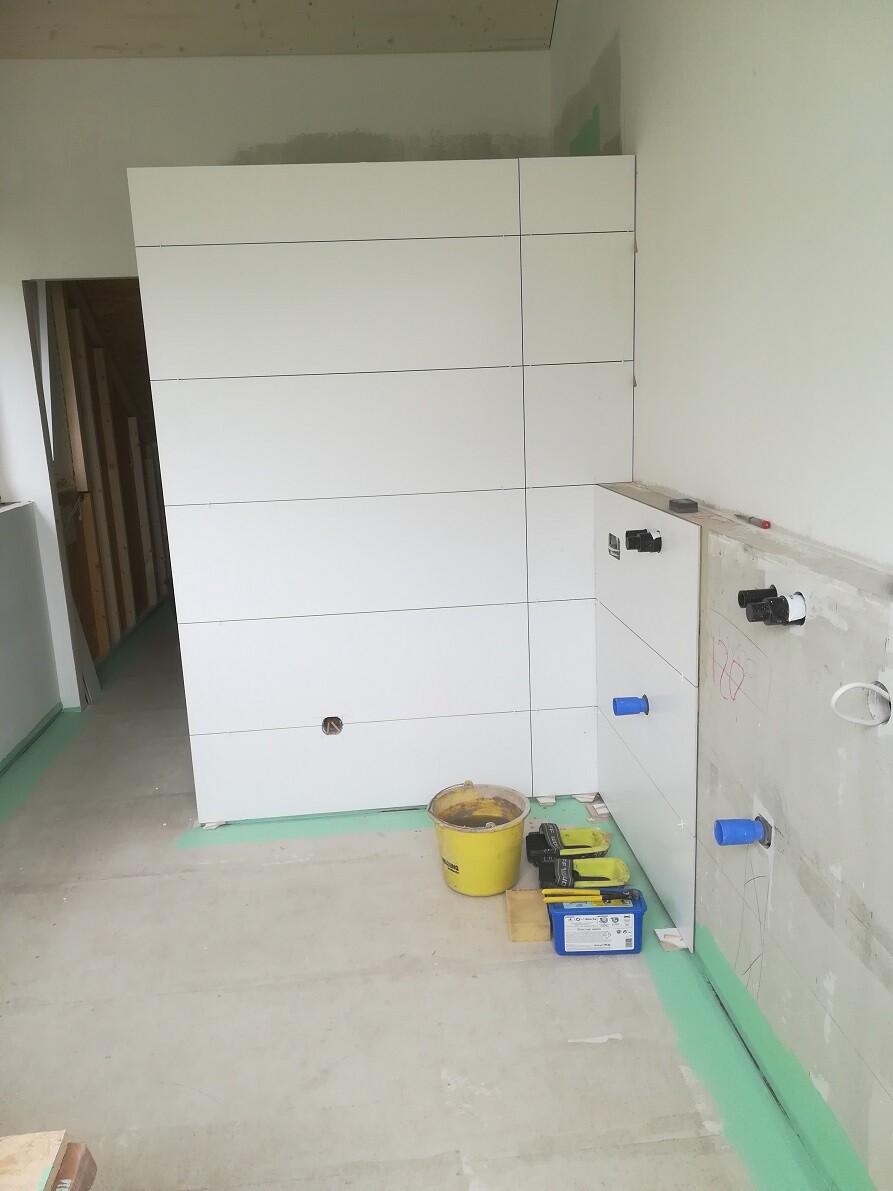 Large white built-in cabinet being installed; tools, buckets, and materials are on the floor.