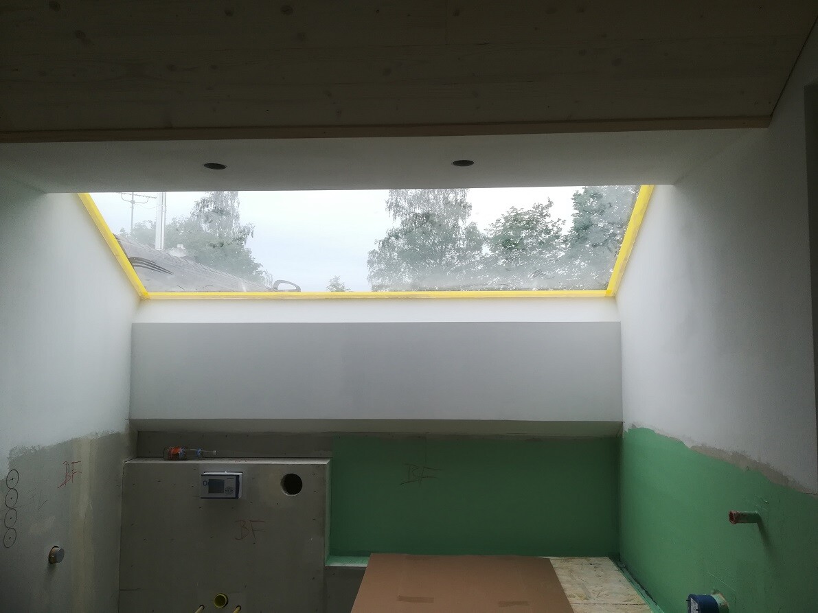 Unfinished interior with yellow skylight frame, green and white walls, construction site.
