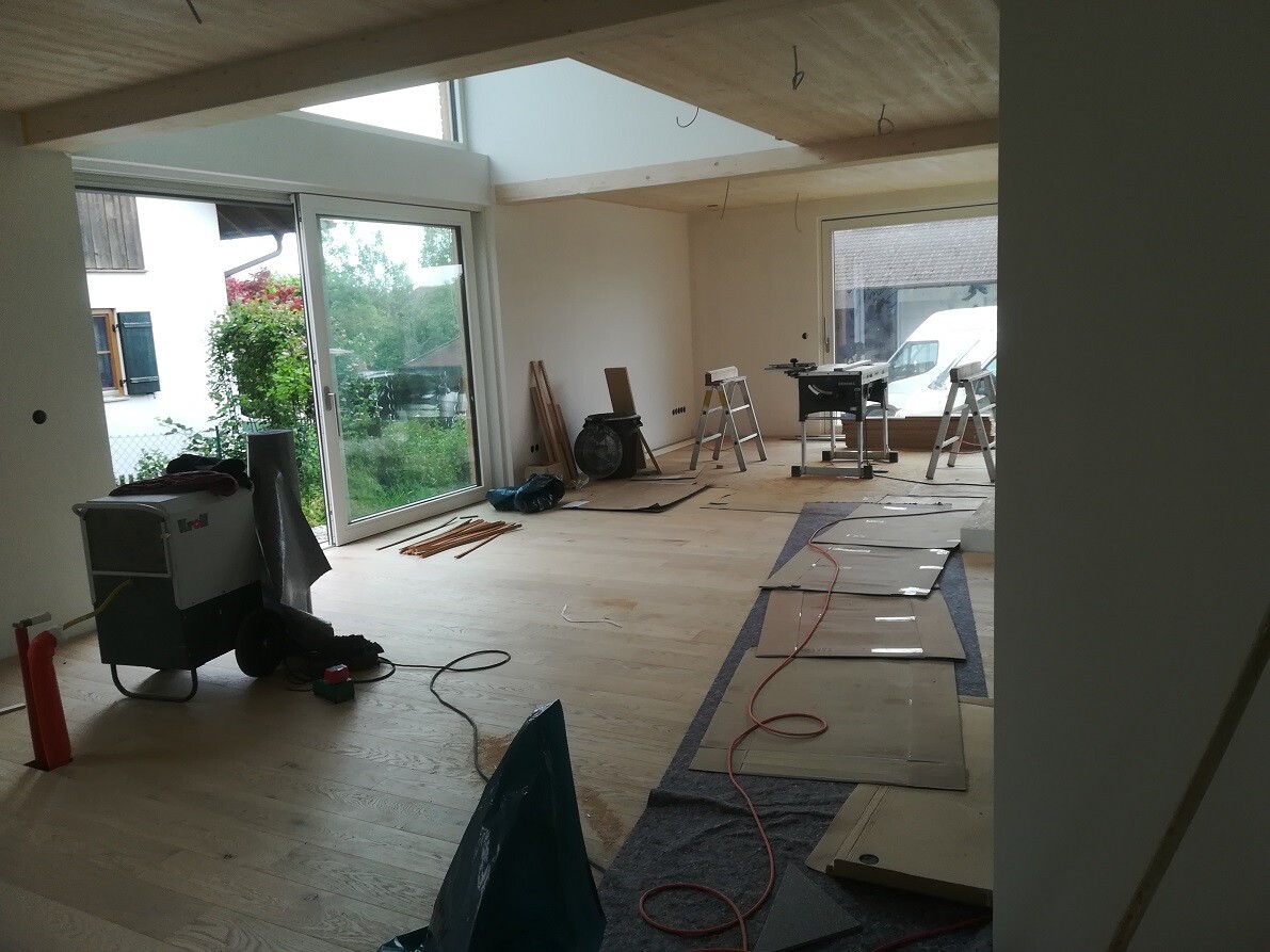 Renovation room under construction: tools, ladder, wooden floor, glass sliding door to the outside.