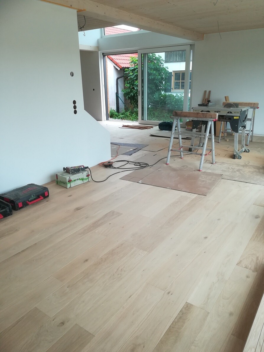 Interior of a renovation site with wooden floor, saws, workbenches, and cables.