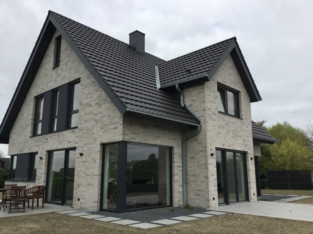 Modern two-story house with brick facade, large glass windows, and terrace.