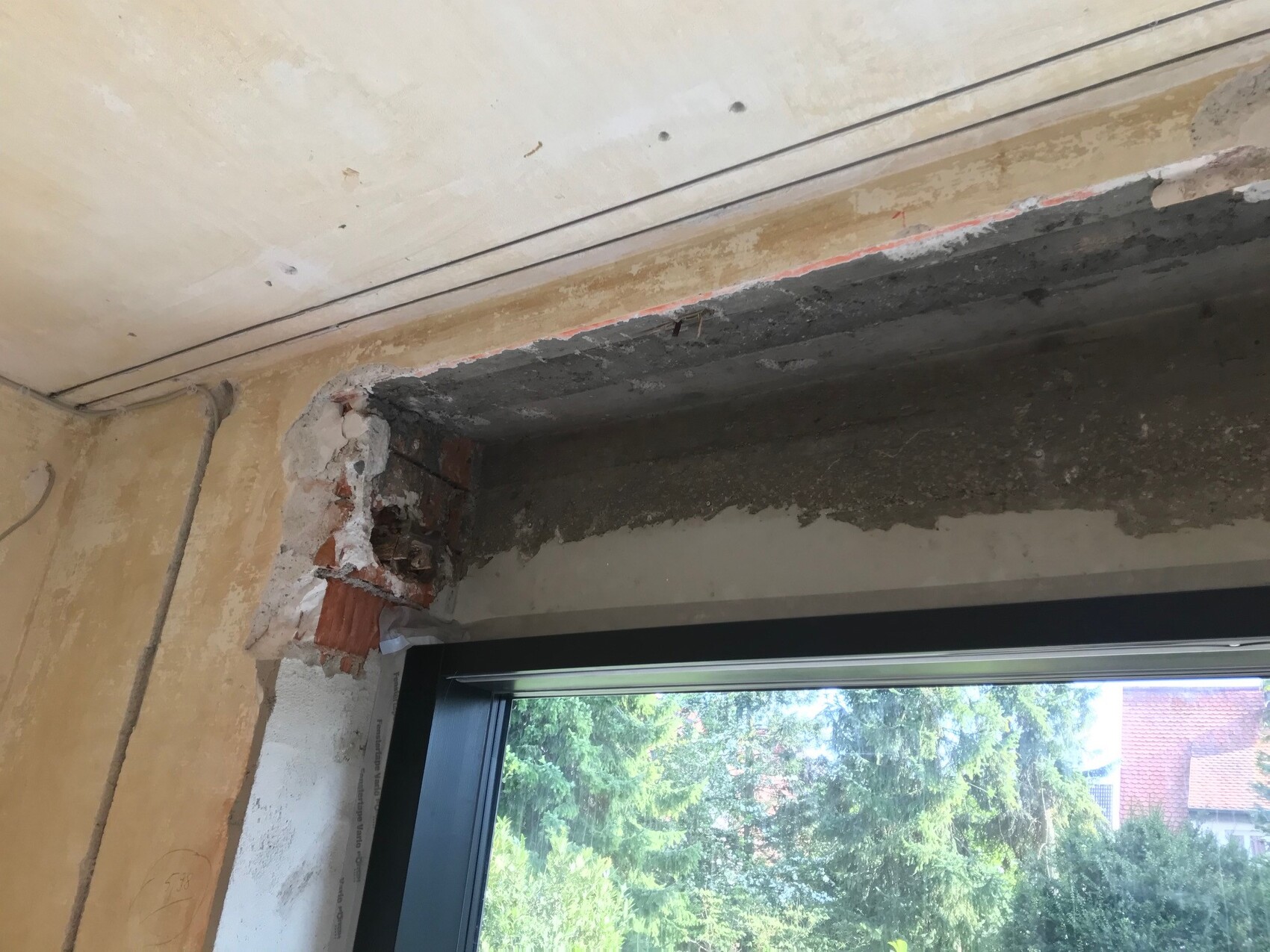 Innenausbau: Wanddurchbruch nahe Fenster, ungeputzte Flächen und sichtbare Rohbauarbeiten
