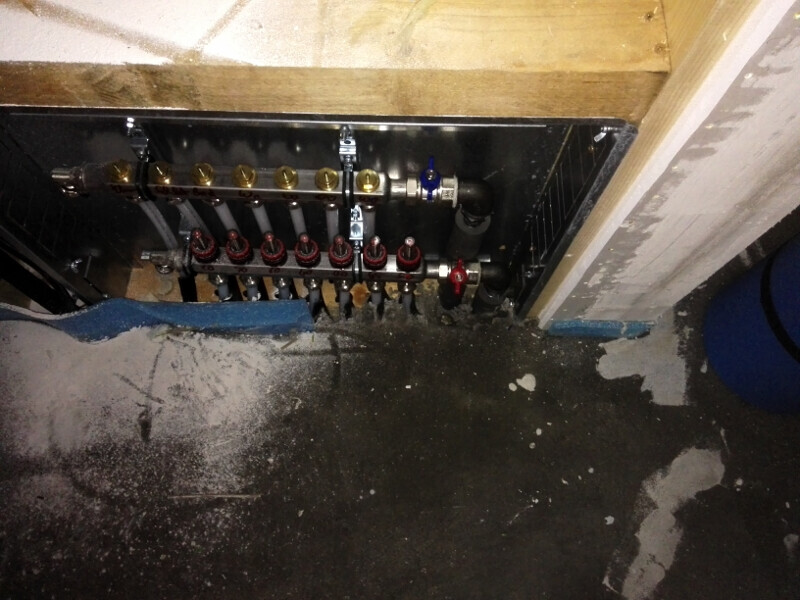 Manifold with valves and pipes behind a partition wall in the basement.