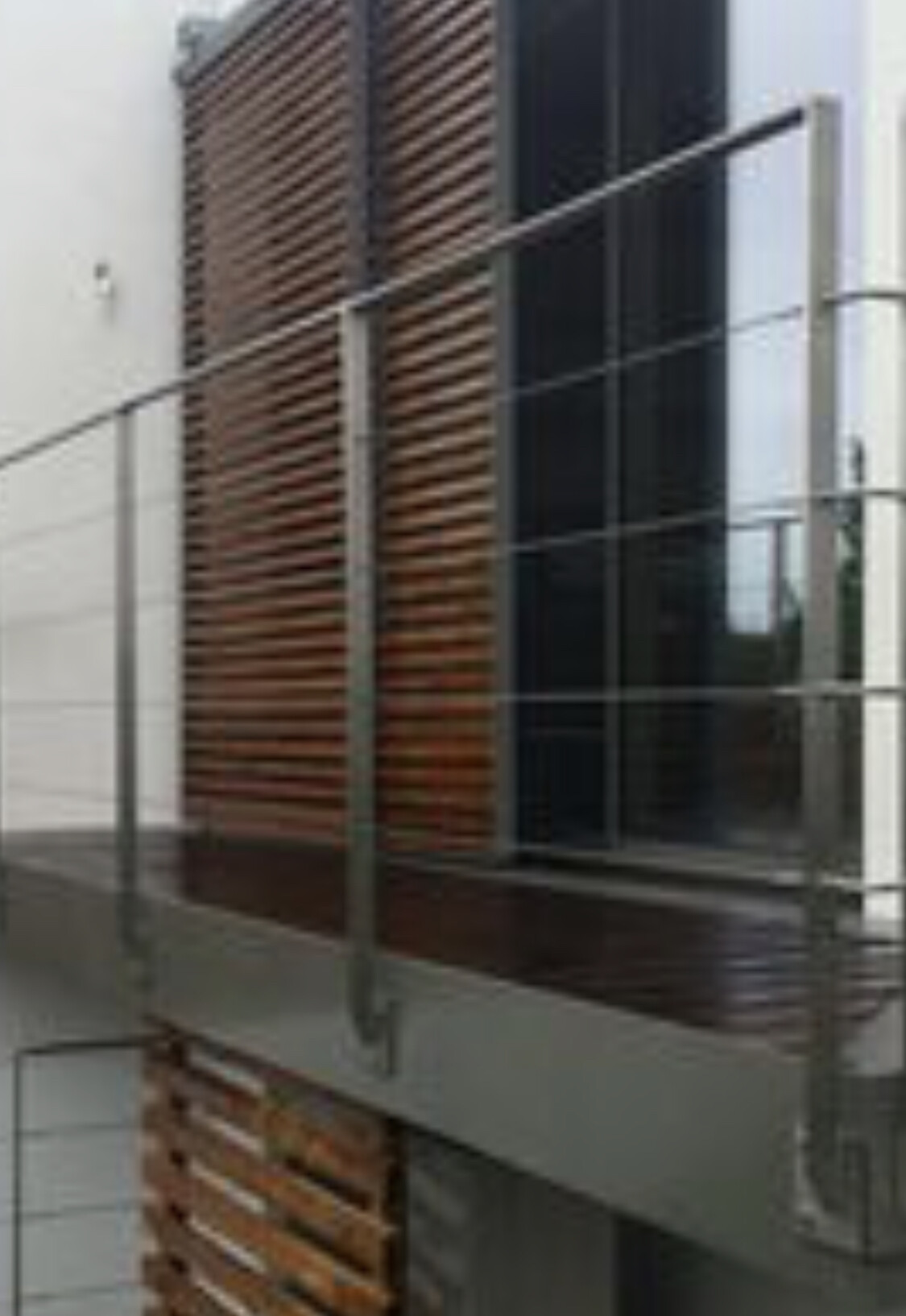 Moderne Hausfassade mit vertikalen Holzlamellen und großen Glasfenstern.