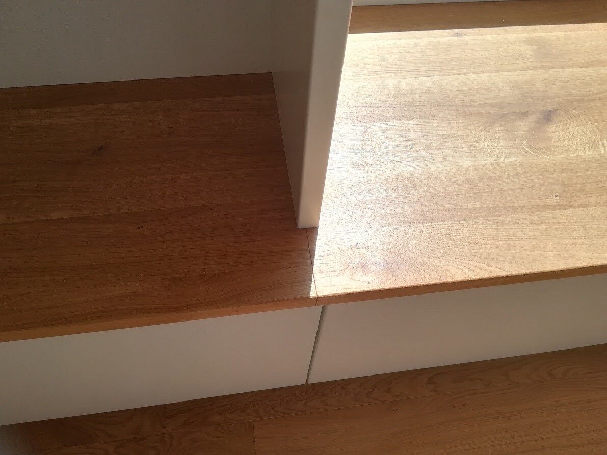 Close-up of a white cabinet with wood-colored top and bottom surfaces and wood grain.