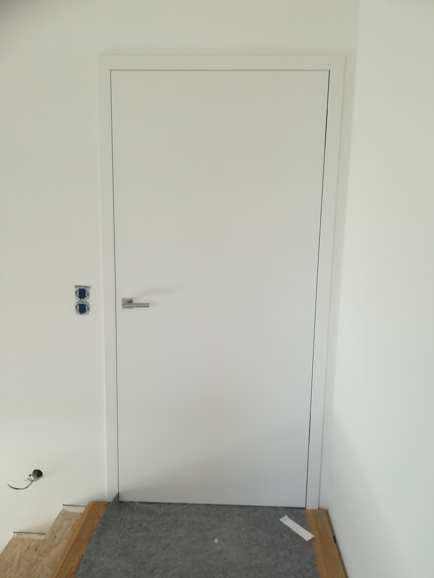 White interior door with metal handle; left wall with unfinished electrical installations