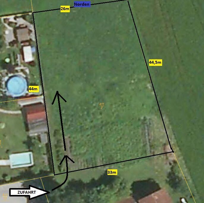 Satellite image of a rectangular plot with boundary lines, measurements, and driveway.
