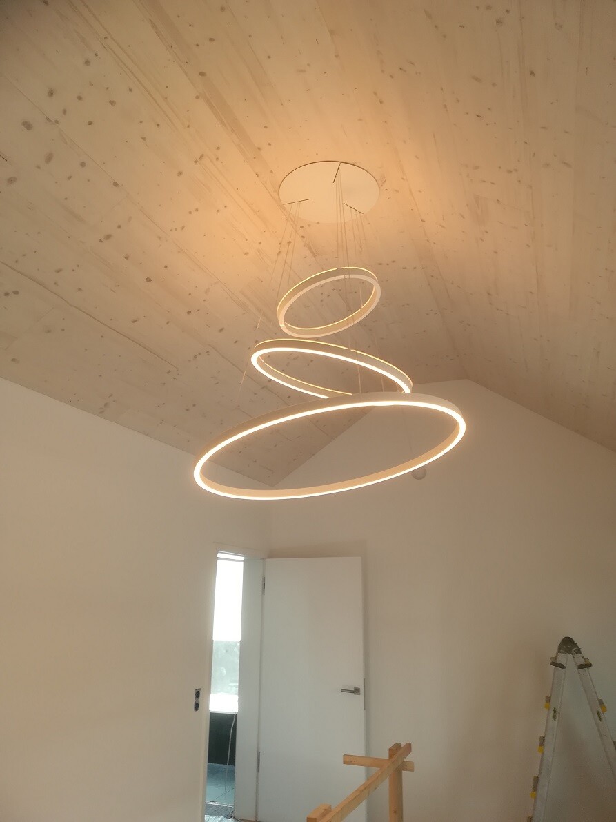 Modern interior with a hanging LED ring lamp consisting of three circles on the ceiling, open doorway.