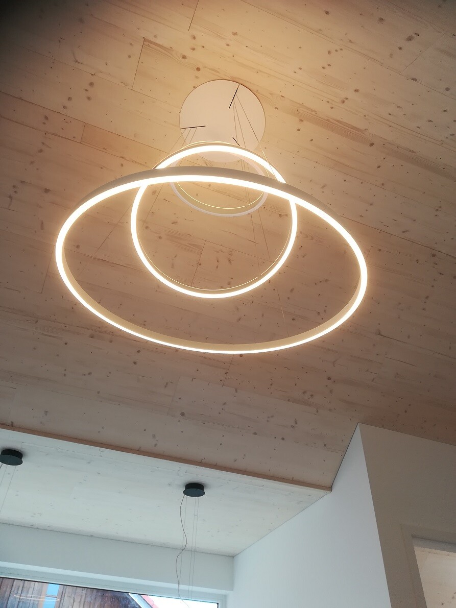 Modern LED ring lamp with two circles on a wooden ceiling, viewed from below.