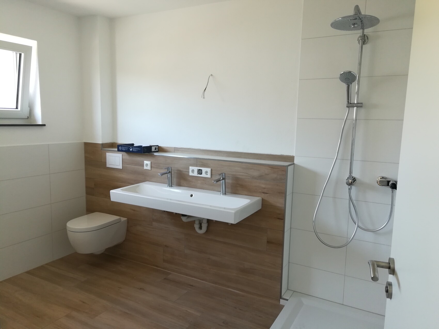 Modern bathroom with wall-mounted sink, wall-hung toilet, and shower with rain showerhead.