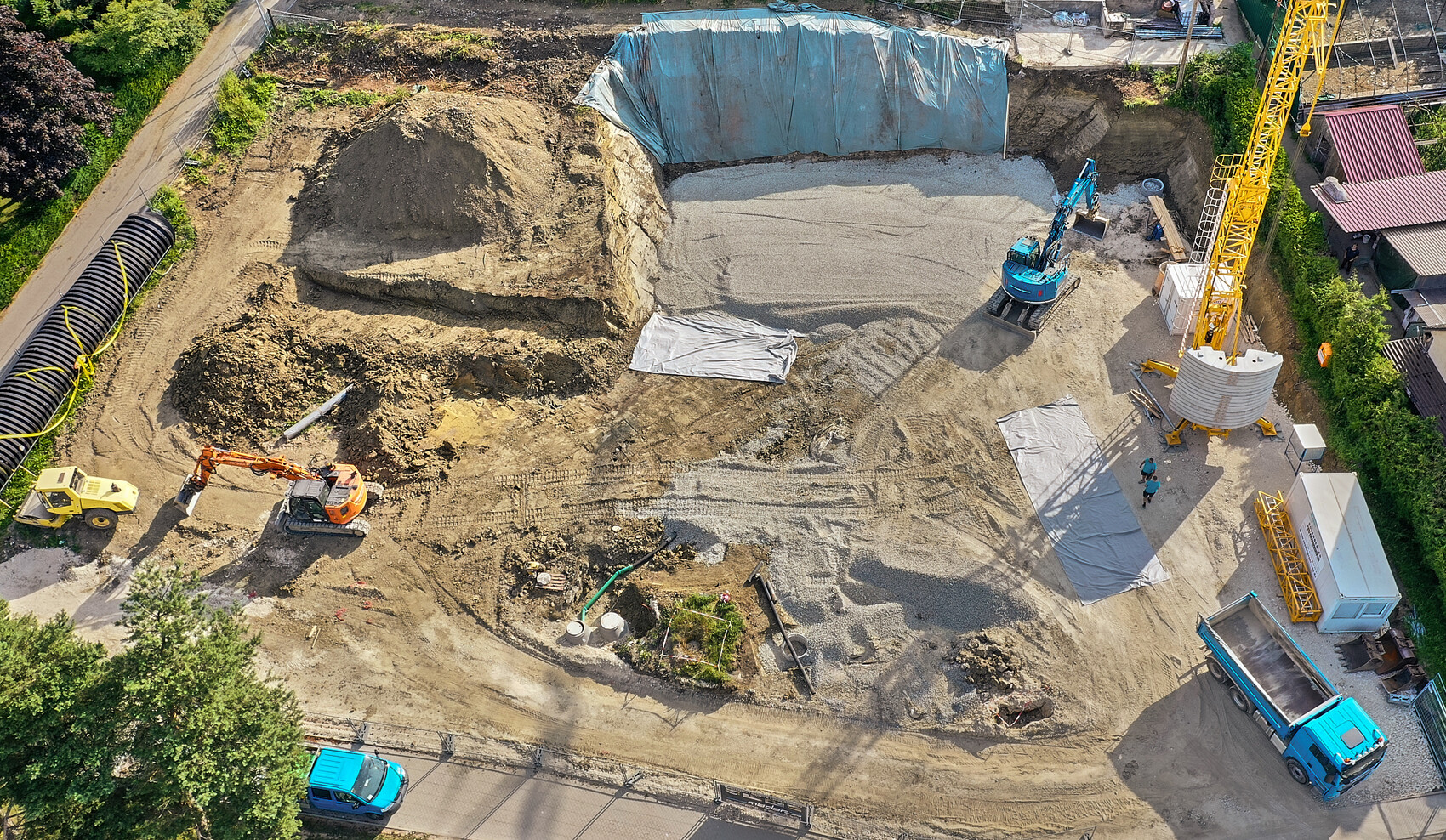 Bird’s eye view: construction site with large excavation pit, excavator, crane, gravel, truck