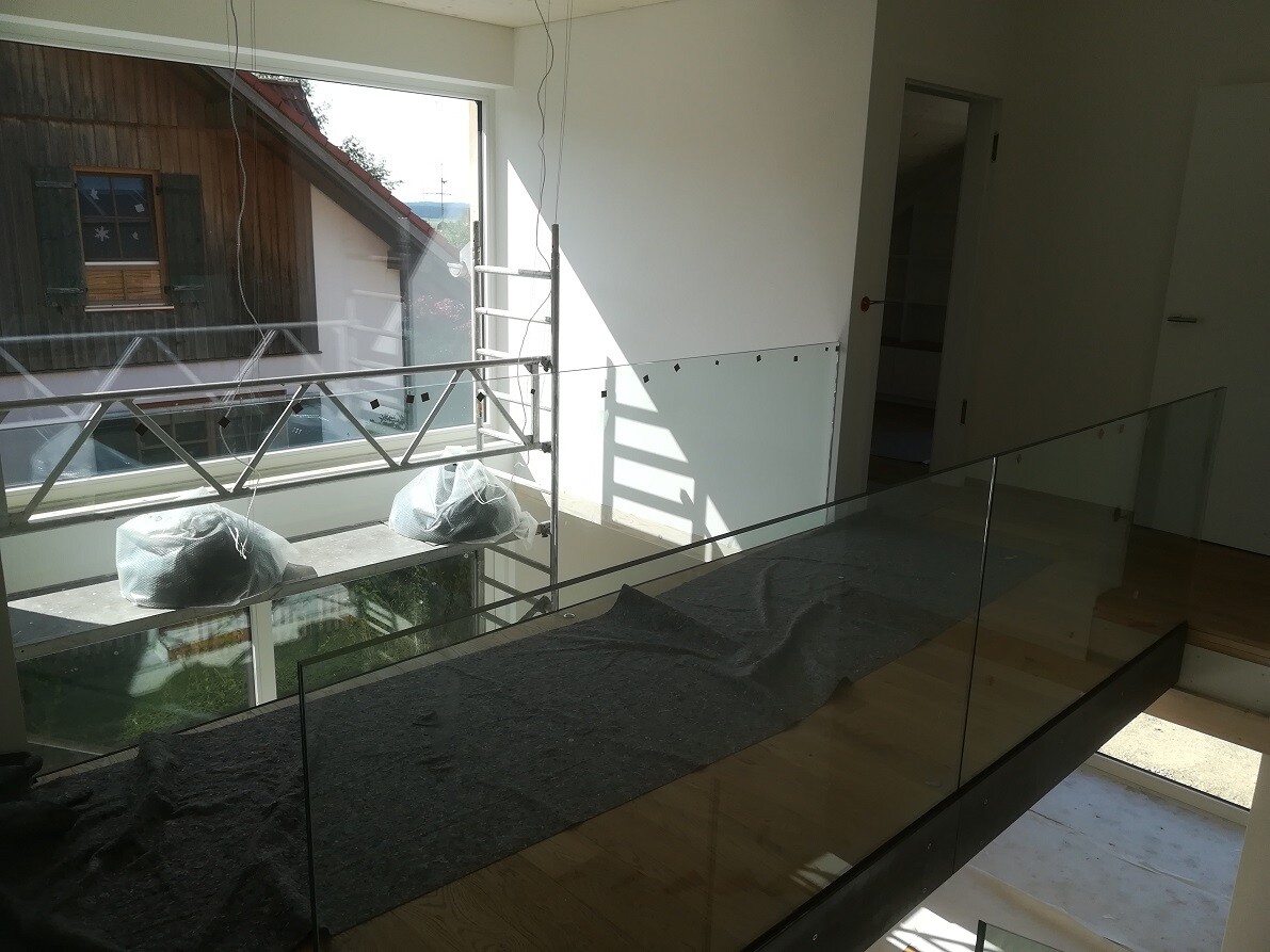 Interior of a new build with glass railing, wooden floor, and scaffolding outside