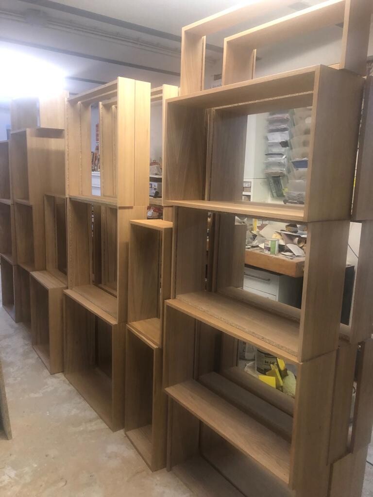 Multi-part wooden shelves in dark wood look, assembled in a workshop.