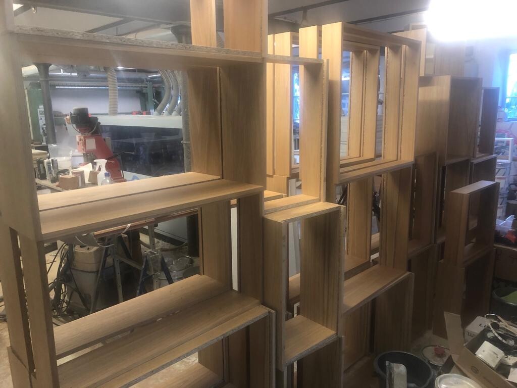 Wooden shelves as modular shelving system in a workshop, machines in the background