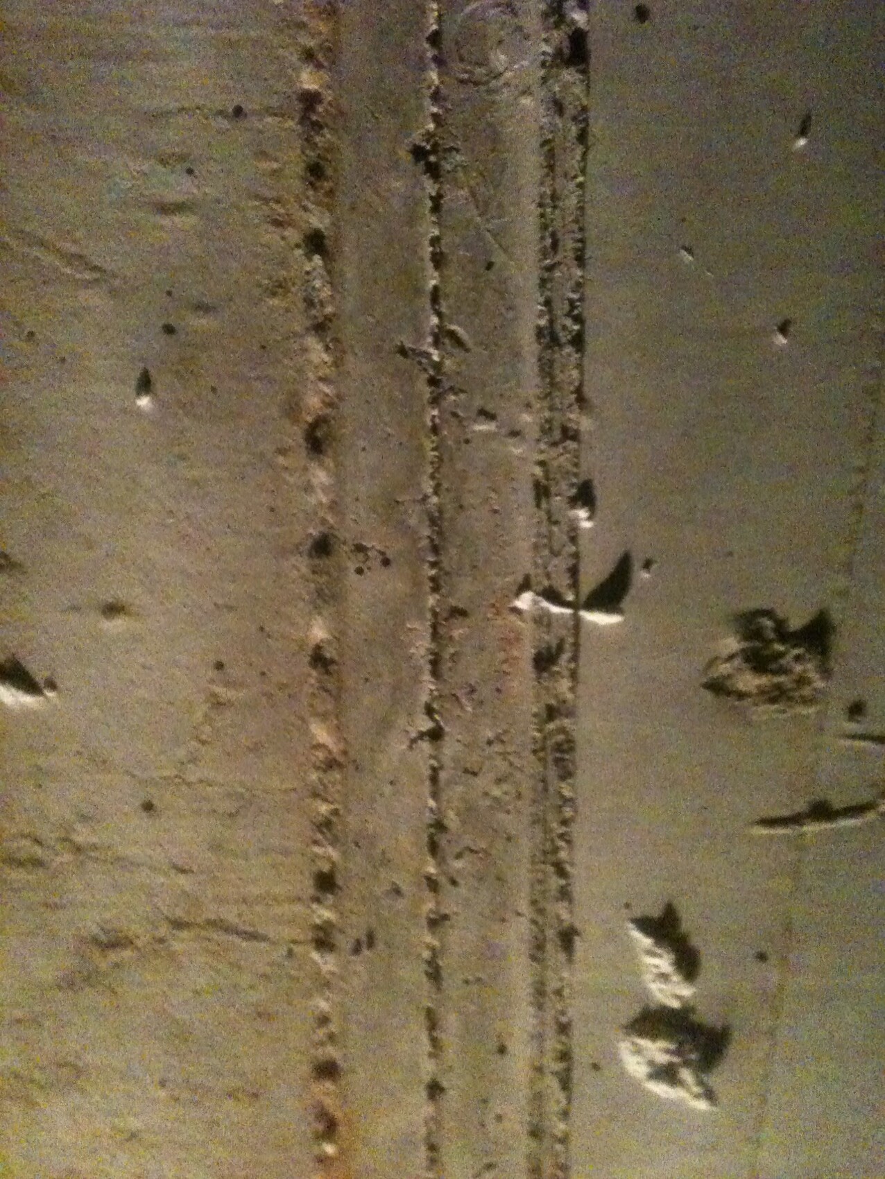Rough concrete wall with vertical cracks and flaking plaster.