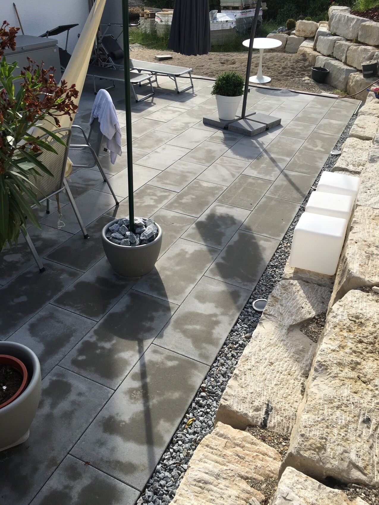 Modern terrace with gray paving slabs, lounge furniture, planter boxes and stone wall