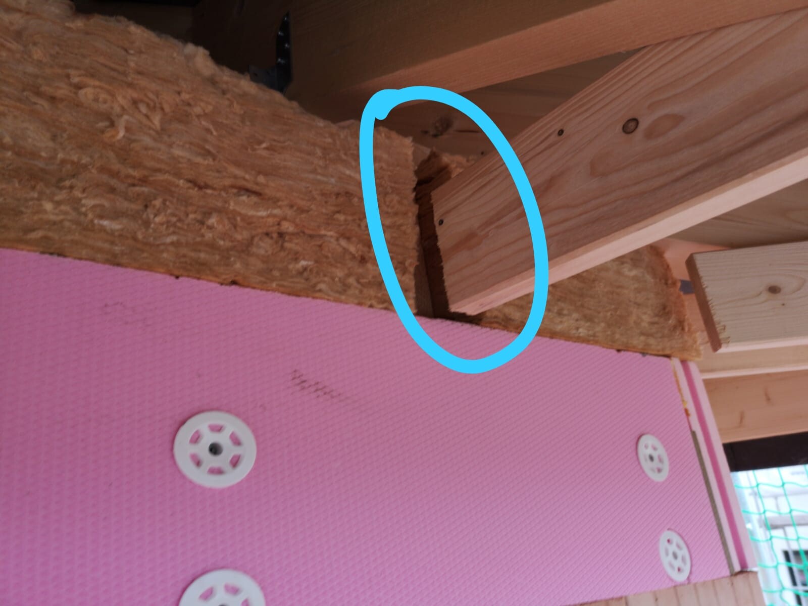 Interior view of a construction site: wooden beams, insulation, and visible tongue-and-groove joint