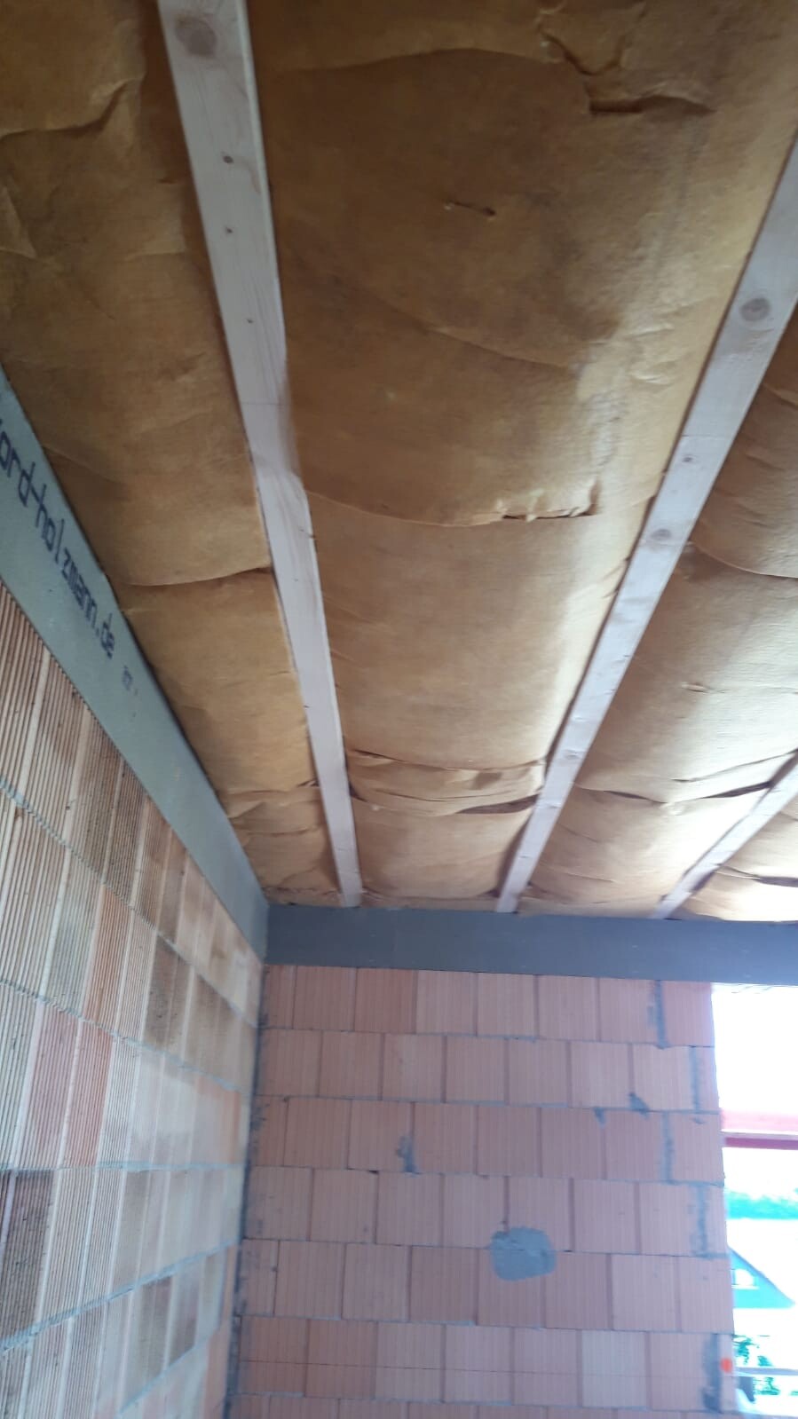 Unclad ceiling with mineral wool insulation between rafters during construction phase