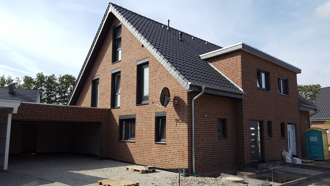 Red brick house with pitched roof, satellite dish, carport and building plot