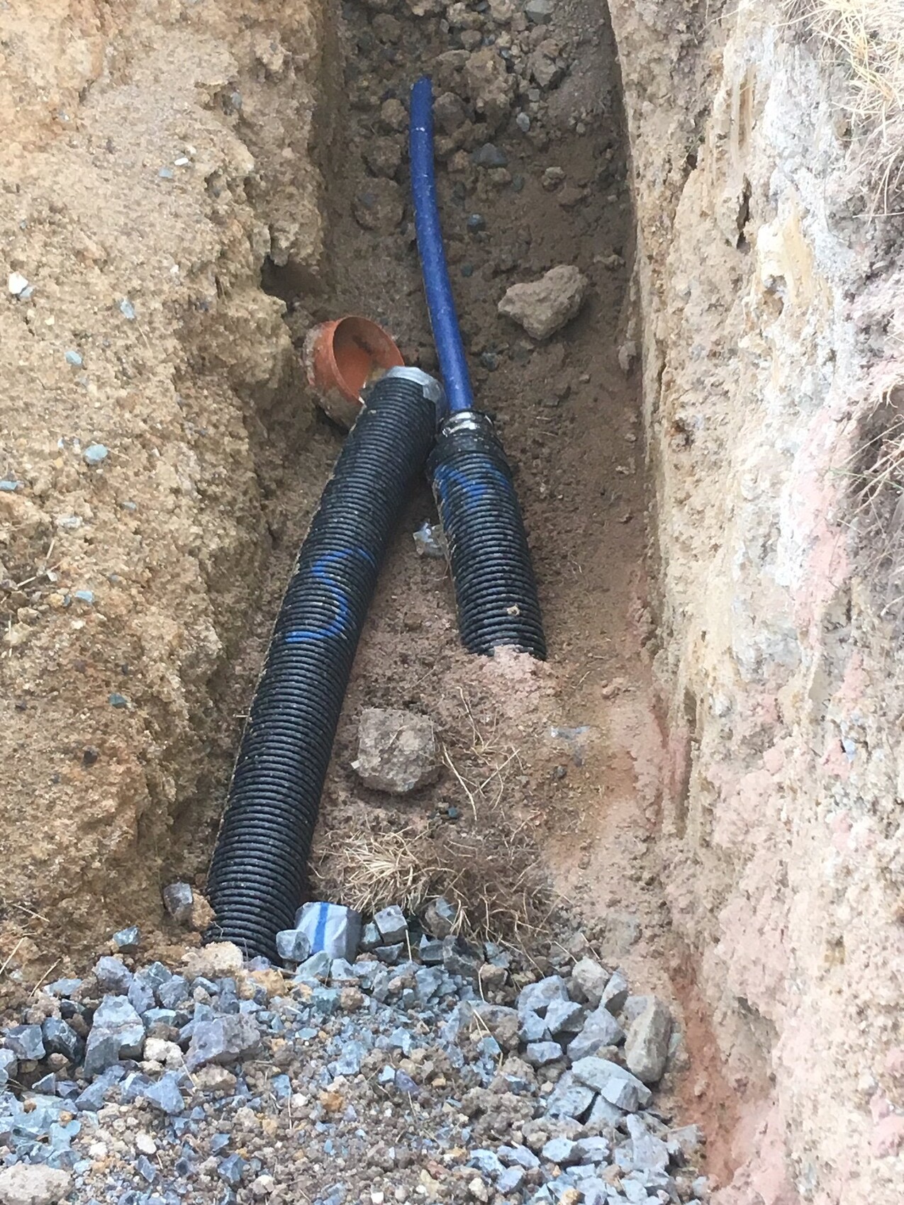 Trench with blue pipes and gravel during foundation construction