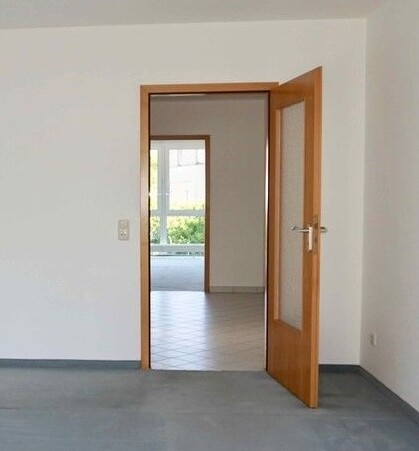 Bright interior with open wooden door, view into adjacent room