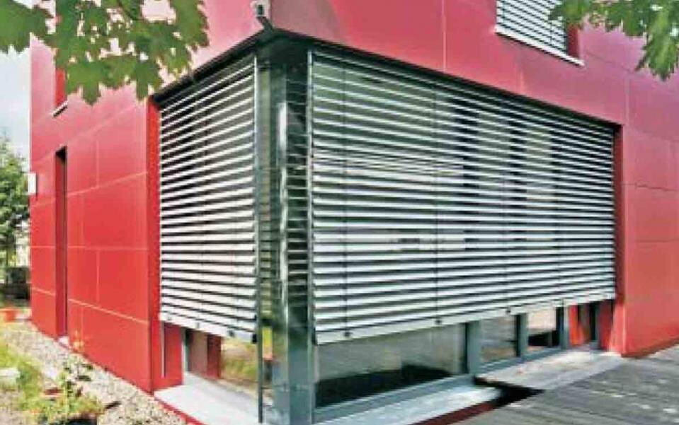 Red building with large windows and horizontal metal slatted roller shutters