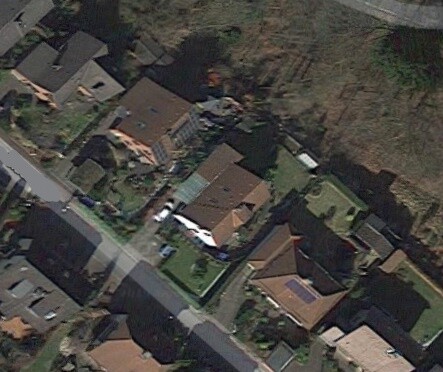Aerial view of a residential area with houses, gardens, and streets from a bird’s-eye perspective.