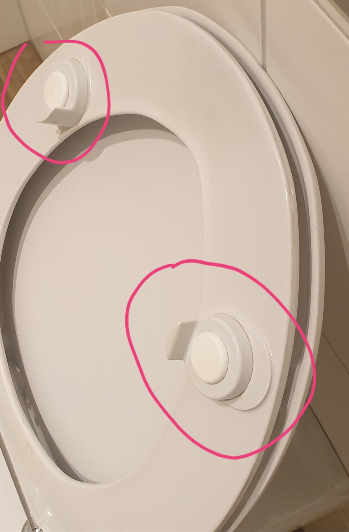 Close-up of a toilet seat with mounting caps on the edge